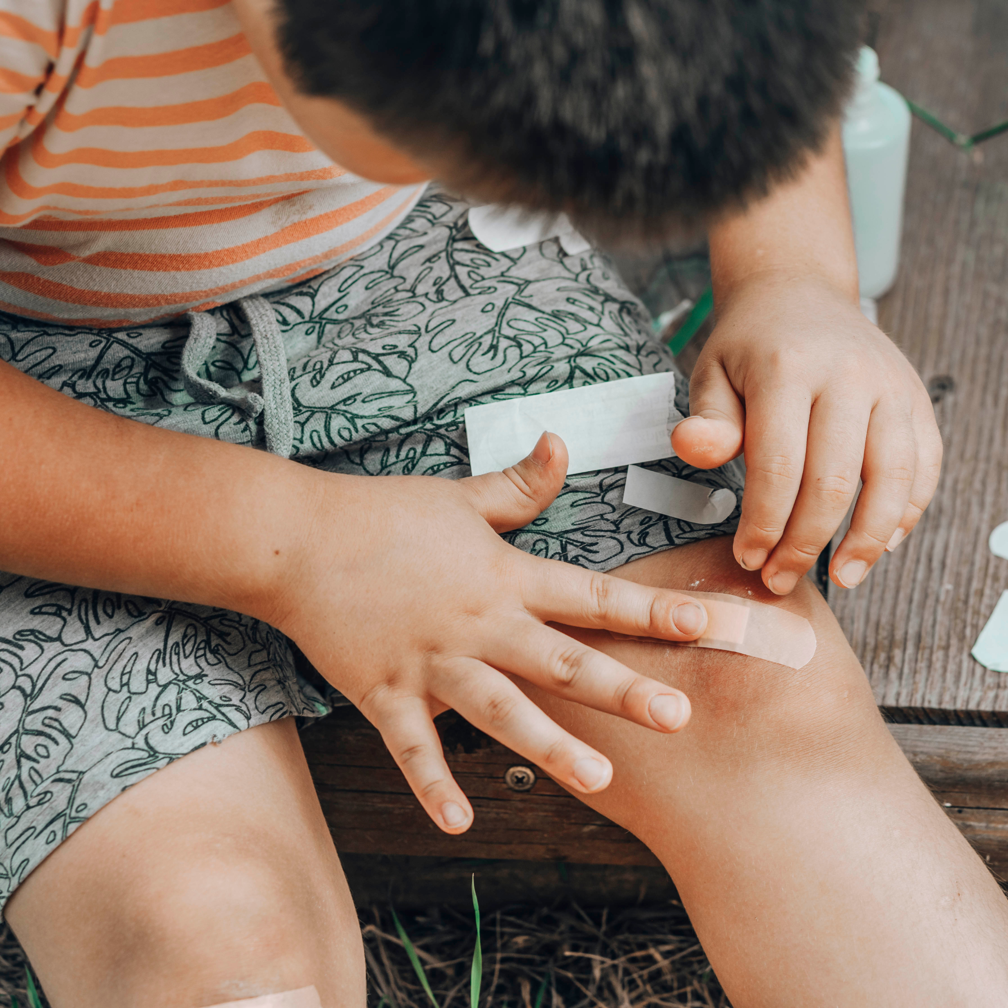 child putting plaster on bruised knee